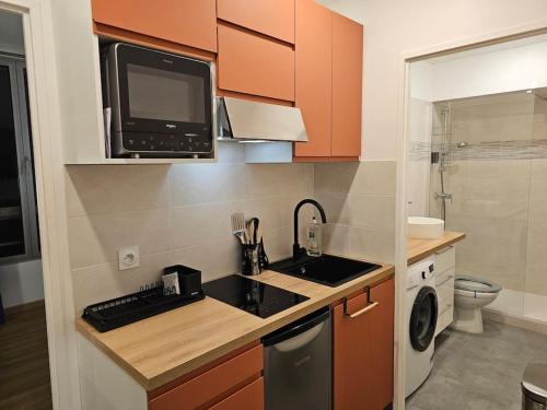 une petite cuisine avec un évier et un micro-ondes dans l'établissement Studio Paris Clichy, à Clichy