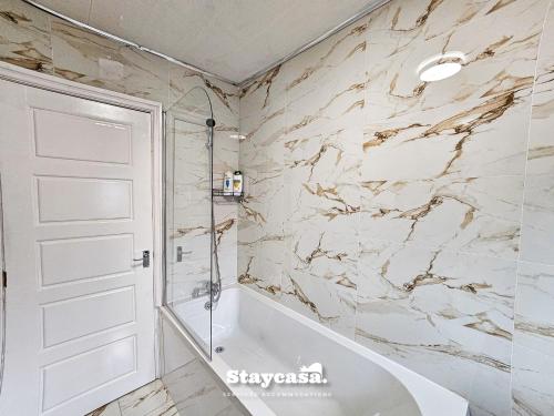 baño con bañera blanca y paredes de mármol en Modern & Spacious 5-bedroom House With Game Room en Mánchester