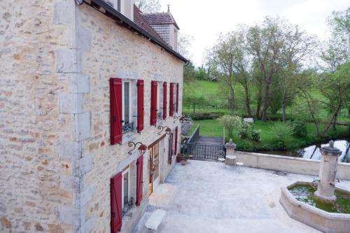 ein Steingebäude mit roten Rollläden und einer Treppe in der Unterkunft Moulin de Petoulle in Charenton sur Cher