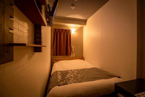 - un petit lit dans une petite chambre avec fenêtre dans l'établissement Hotel Peace (Adult Only), à Tokyo