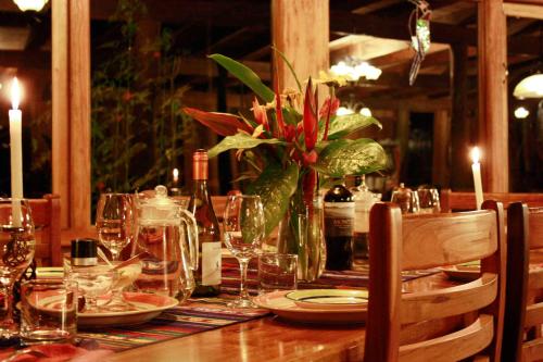 a table with glasses and a vase of flowers on it at Casa Divina Eco Lodge in Mindo
