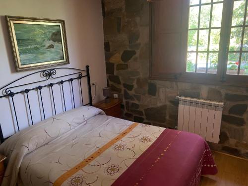 a bedroom with a bed and a stone wall at Hotel Rural Camino Medulas in Ponferrada