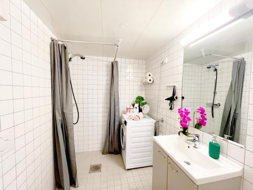 a white bathroom with a shower and a sink at City center flat with balcony & free parking in Oslo