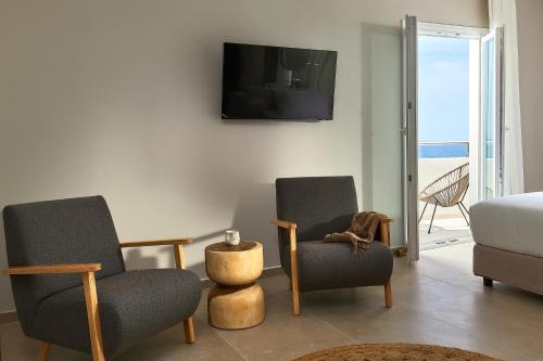 a living room with two chairs and a bed and a television at Lotus Rise Hotel - Adults Only in Hersonissos