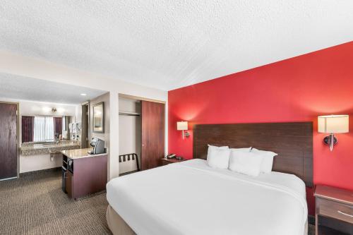 a large bed in a hotel room with a red wall at Quality Inn in Columbus