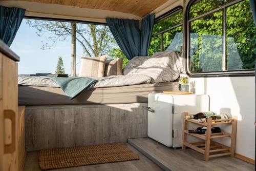 a bedroom in a tiny house with a bed and a refrigerator at Bus Ikarus in Prievidza