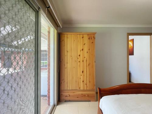 a bedroom with a wooden closet and a sliding glass door at YF Home Sweet Home FREE WIFI 4 bedroom beautiful house in Craigieburn