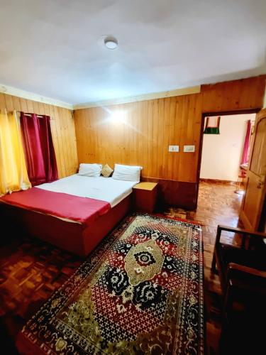 Kleines Zimmer mit einem Bett und einem Teppich in der Unterkunft Snow land cottage in Manali