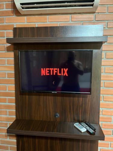 a television with the words netflix on a brick wall at Pousada Nosso Bosque in Porto Belo
