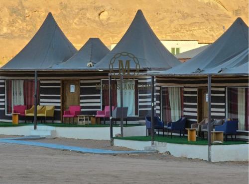 un edificio con sedie viola e rosa di fronte ad esso di Moon Island Camp a Wadi Rum