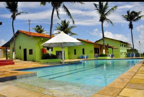 ein Pool mit einem weißen Regenschirm neben einem Gebäude in der Unterkunft Pargos Club de Salinas in Salinópolis