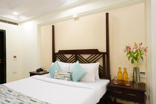 a bedroom with a bed with white sheets and blue pillows at Shree Vallabh Vilas Lords Plaza Nathdwara - Pure Veg in Eklingji
