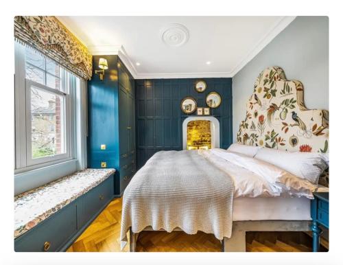 a bedroom with blue walls and a bed and a window at Boutique Studio in Putney,Wimbledon in London