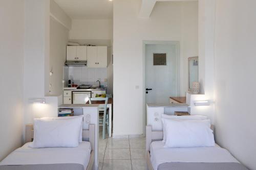 a white living room with two couches and a kitchen at Giant Woman in Tsoútsouros