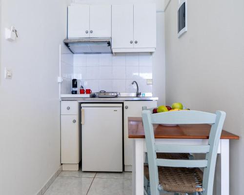 a kitchen with white cabinets and a table with fruit on it at Giant Woman in Tsoútsouros