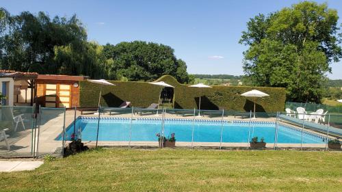 une piscine avec une clôture à côté d'une maison dans l'établissement Gîte La Marteille, à Saint-Privat-des-Prés