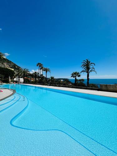 a large swimming pool with the ocean in the background at Luxurious Monaco Flat: Stunning Views & Amenities in Monte Carlo
