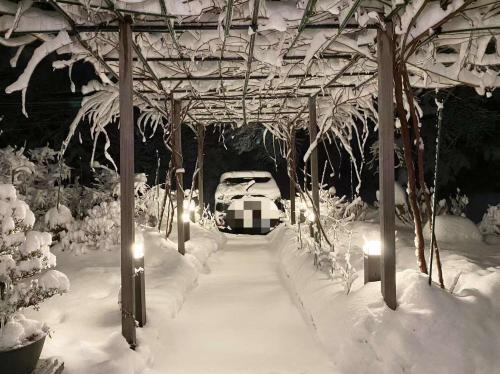 ein Auto, das unter einem schneebedeckten Pavillon geparkt ist in der Unterkunft Pension Lanpou in Fujikawaguchiko