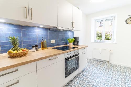 a kitchen with white cabinets and blue tiles at Ferienwohnung zur Burg in Stolpen
