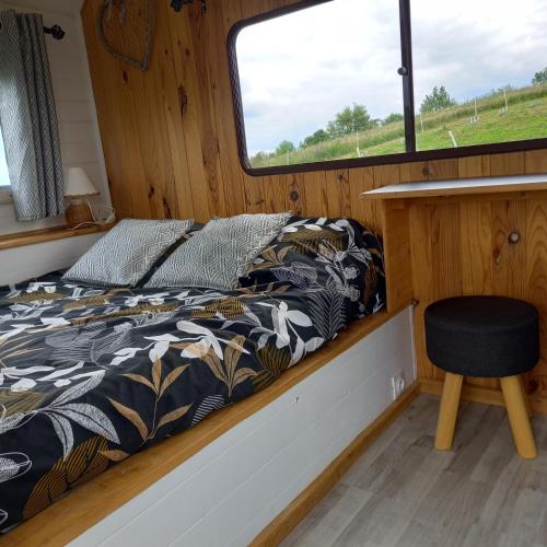 a bed in the back of a boat with a window at Camping car vintage in Saint-Barthélemy-le-Plain