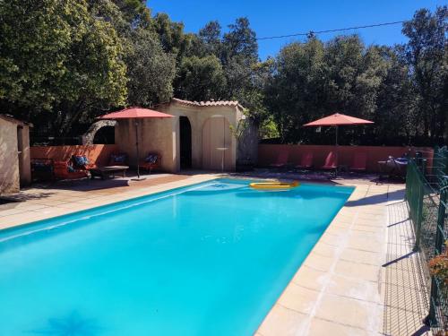 - une piscine dans une cour avec des parasols dans l'établissement Villa Dervonnae, la Provence à l'ombre des Chênes, à Tavernes