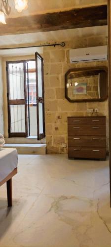 a room with a dresser and a stone wall at Vallettastay City break apartments in Valletta