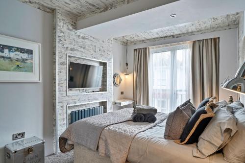a bedroom with a large bed and a tv on a wall at Finest Retreats - The Old Library in Dartmouth