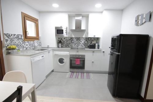 cocina con nevera negra y lavavajillas en Taraska II - Duplex en centro neuralgico de Bermeo, en Bermeo
