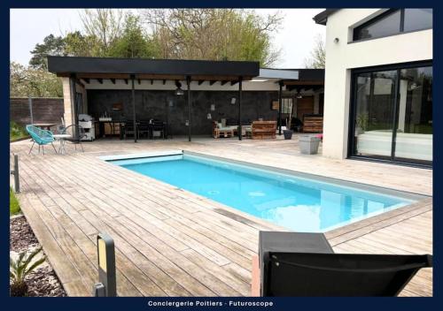 une piscine avec une terrasse en bois et une maison dans l'établissement La villa de Beauvoir, à Mignaloux-Beauvoir