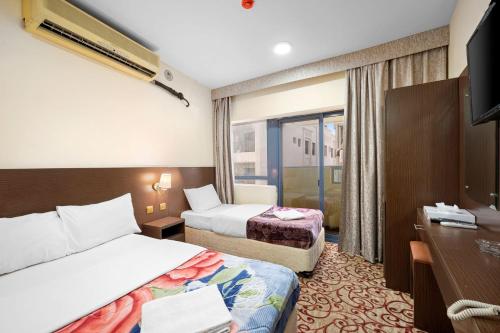 a hotel room with two beds and a television at Najiba Hotel in Dubai