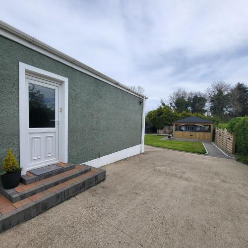 uma casa verde com uma porta branca e uma entrada em Woodside guest house em Castlerock