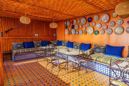 a room with couches and tables and plates on the wall at Riad el wazzania in Rabat