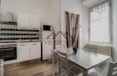 a kitchen with a table and a white refrigerator at Casa vacanza Pino in Follonica