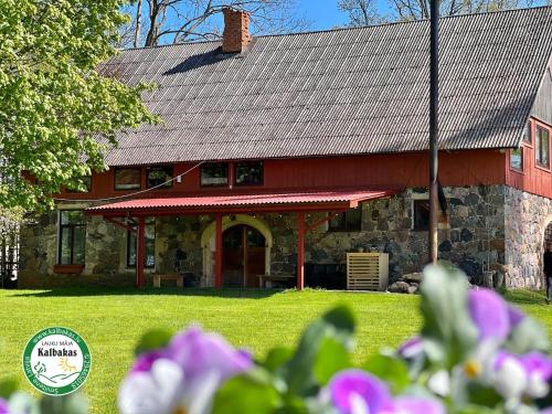 a red and stone house with flowers in front of it at Guest House Kalbakas in Smiltene