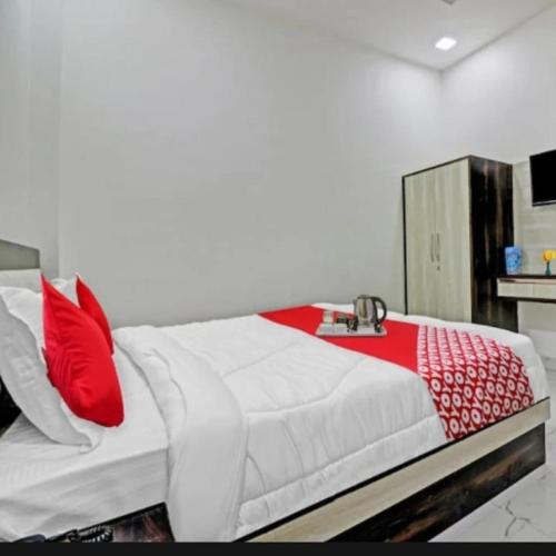 hotel chahat palace في آغْرا: غرفة نوم بسرير ابيض ومخدات حمراء