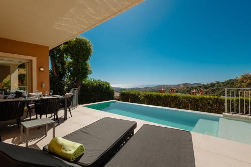 Cette villa dispose d'une piscine avec une table et des chaises. dans l'établissement Private infinity pool with sea views in La Mairena, Marbella, à Sitio de Calahonda
