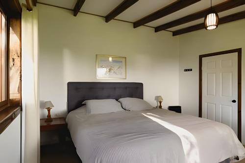 una camera da letto con un grande letto con lenzuola bianche di Acogedora casa en la costa de Pelluhue a Chanco