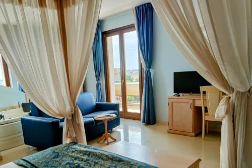 - une chambre avec des rideaux bleus, une chaise bleue et une télévision dans l'établissement UNICO Albatres Palace Salento by Life Resorts, à San Vito dei Normanni