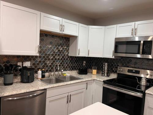 a kitchen with white cabinets and a sink and a microwave at Healing Haven King Bed Suite in Dallas