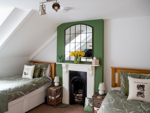 a bedroom with a green accent wall and a fireplace at The Wheelhouse in Fowey