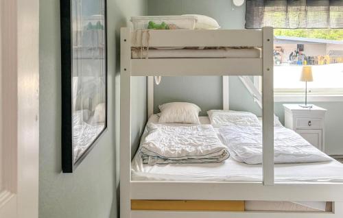 Litera con sábanas blancas y almohadas en Amazing Home In Uddevalla With Kitchen, en Uddevalla