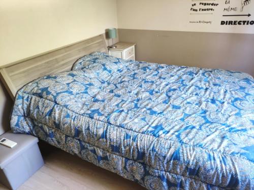 uma cama com um edredão azul num quarto em Jolie bas de villa entre mer et campagne em Ollioules