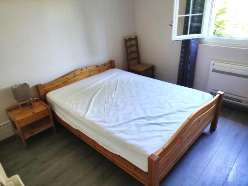 um quarto com uma cama de madeira e um colchão branco em Jolie bas de villa entre mer et campagne em Ollioules