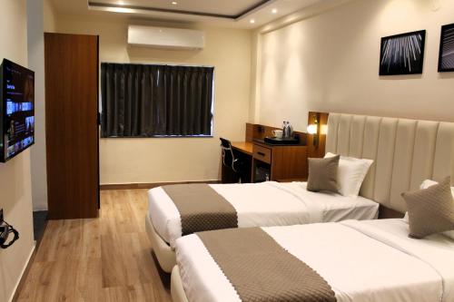 a hotel room with two beds and a television at The Vantage Inn, near US Consulate Gachibowli Hyderabad in Hyderabad