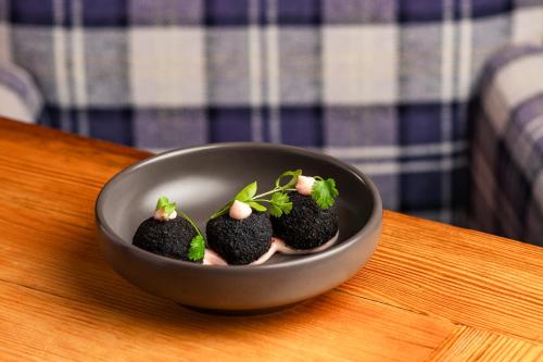 a bowl with three black foods in it on a table at The Swan Hotel, Stafford, Staffordshire - The Coaching Inn Group in Stafford