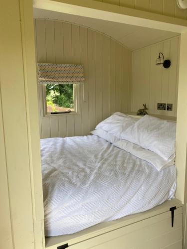 a white bed in a room with a window at Willow Shepherd Hut in West Row