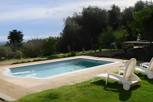 a swimming pool with two lawn chairs next to it at Cabaña en la costa de Pelluhue in Pelluhue