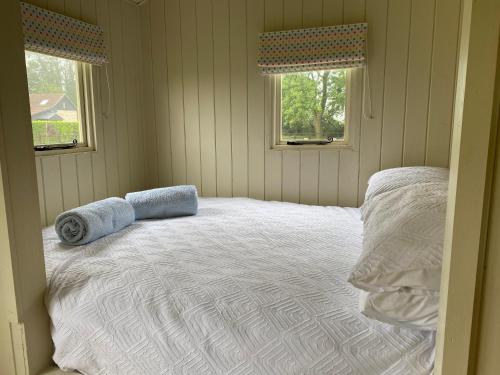 a bedroom with a bed with two pillows and two windows at Willow Shepherd Hut in West Row