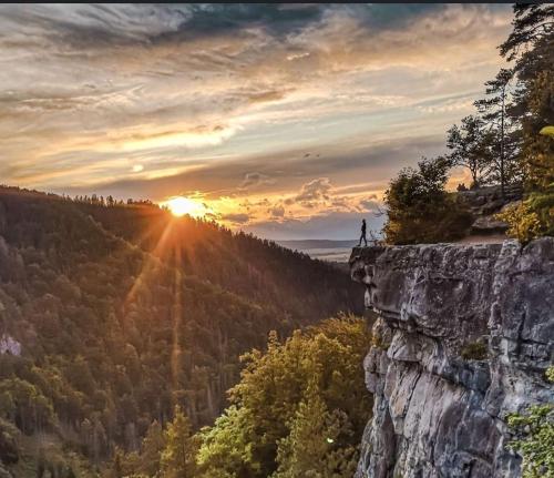 a person standing on the edge of a cliff watching the sunset at Chata JÚLIA in Vernár
