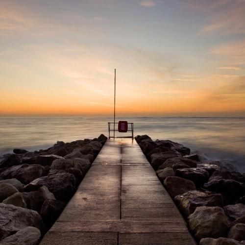 a wooden pier leading into the ocean at sunset at Holiday home with Panoramic Sea Views in Lytchett Minster
